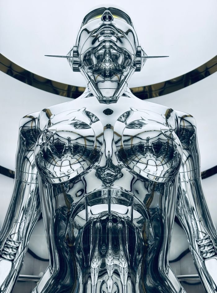 A close-up view of a metallic futurist robot sculpture indoors.