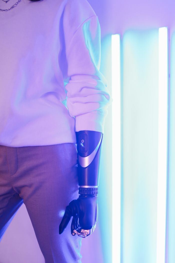 Stylish woman with prosthetic arm and neon lights illustrating modern technology.